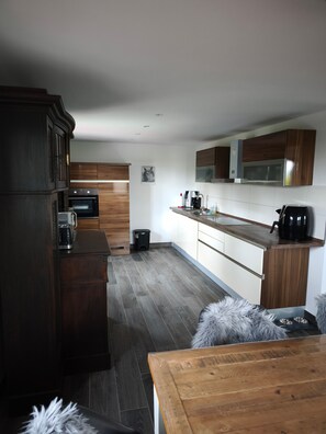 A modern kitchen with dark wood cabinets, a stainless steel oven, and a microwave. - Holiday Home 'Haus Am Deich' with Terrace, Private Garden & Wi-Fi (Norden)