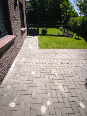 A paved walkway with a brick wall on one side and a grassy area with a fence on the other. - Holiday Home 'Haus Am Deich' with Terrace, Private Garden & Wi-Fi (Norden)