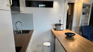 A compact kitchen with a sink, a coffee maker, and a waste bin. - Apartment 'Cap Ferret with Pool Ref. 89' with Shared Pool and Balcony (Lège-Cap-Ferret)