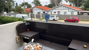 An outdoor seating area with a grill and a basket of seashells. - Apartment 'Cap Ferret with Pool Ref. 89' with Shared Pool and Balcony (Lège-Cap-Ferret)