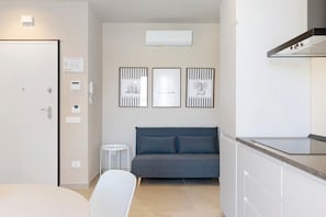 Eine moderne Küche mit Einbauherd, einem grauen Sofa und einem kleinen weißen Tisch.
