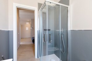 Un baño moderno con ducha envuelta en vidrio, un inodoro y un lavamanos.
