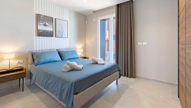 Un dormitorio moderno con una cama grande, mesitas de noche y vistas al exterior.