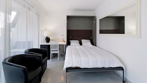 A modern hotel room with a bed, a desk, a chair, and a large window. - Apartment 'Couronne Du Cros' with Sea View, Wi-Fi and Air Conditioning (Cagnes-sur-Mer)