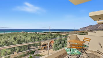 Un balcone con vista sul mare, una sedia di legno e un tavolino.