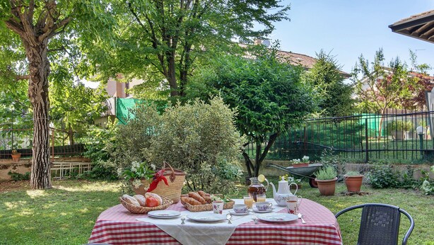 Un tavolo apparecchiato all'aperto con tovaglia a scacchi, circondato da sedie e vari cibi e bevande.