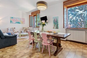 A dining area with a wooden table, floral chairs, a vase with flowers, and artwork on the walls. - 'Casa Cedrus' with Shared Garden (Lainate)