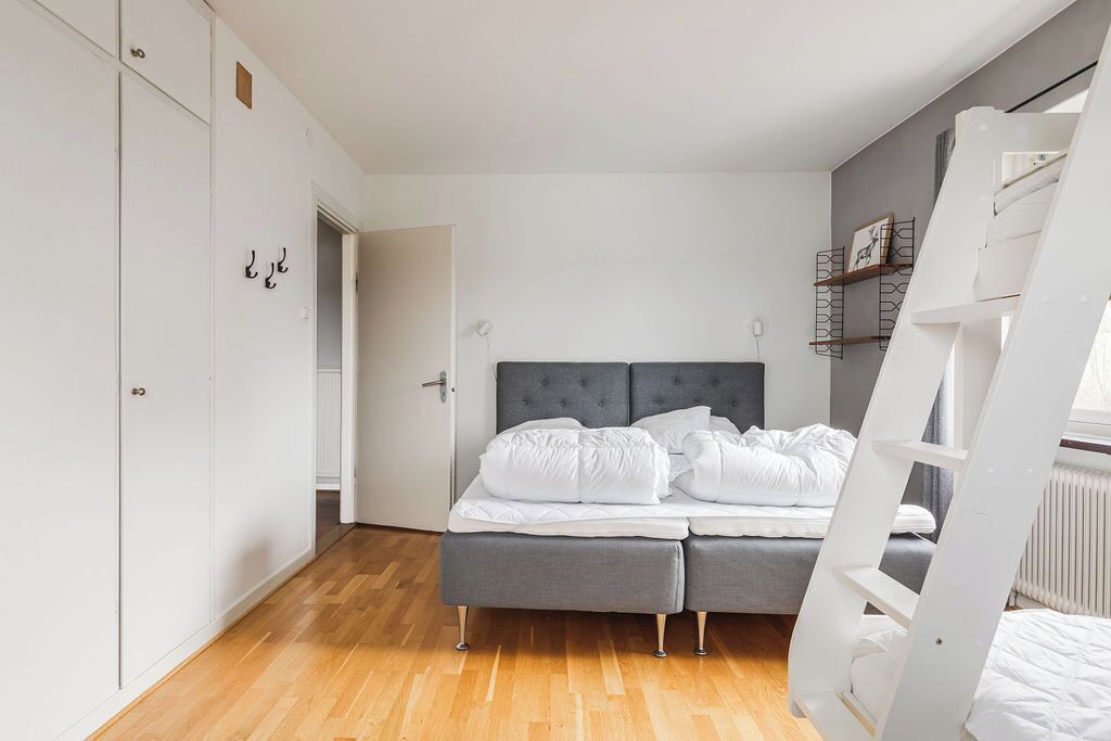 Un dormitorio con cama, armario, escalera y puerta que da a otra habitación.