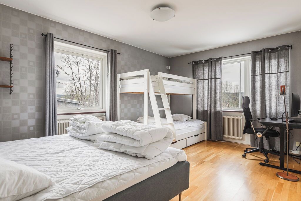 A bedroom with a bunk bed, a desk with a chair, and a radiator.