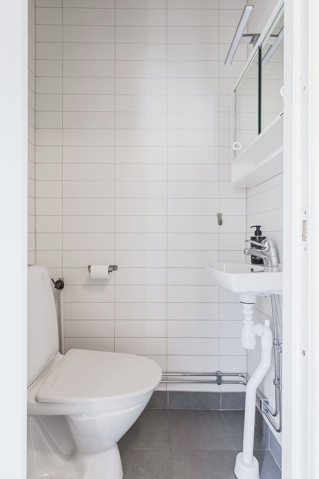 A modern bathroom with a white toilet, a sink, and a shower area.