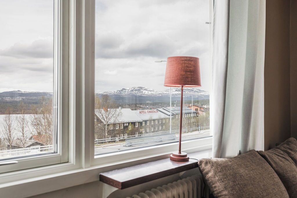 A window with a view of a hotel, a lamp, and a radiator.