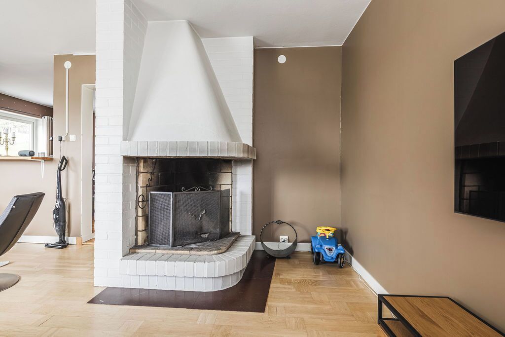 A living room with a fireplace, a sofa, a coffee table, and a TV mounted on the wall.