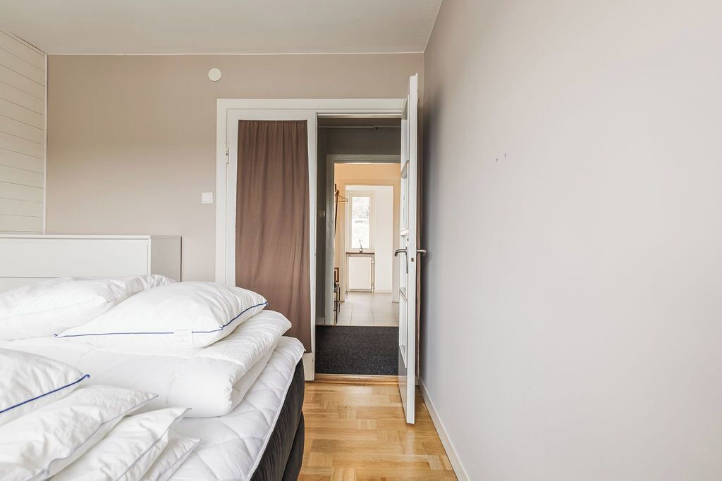 A bedroom with a bed, a door leading to another room, and a hallway.