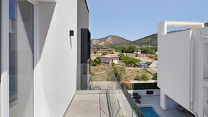 Un balcon doté d’une balustrade en verre, offrant une vue sur une piscine et un paysage montagneux.