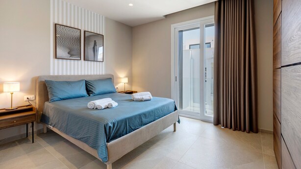 Une chambre d’hôtel avec un lit, des tables de chevet, une lampe, une fenêtre avec des rideaux et une vue sur l’extérieur.