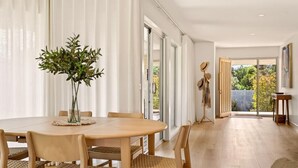 Et moderne spiseområde med et rundt bord, seks stole og en vase med grønne planter.