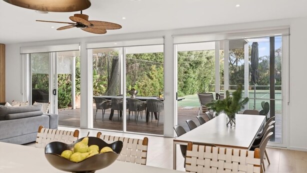 Une cuisine moderne avec un coin repas, de grandes fenêtres et un ventilateur de plafond.