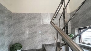 A marble staircase with metal railings, a potted plant, and a world map on the wall. - Slate Majestic 1BHKs Sector 53 Noida (Noida)