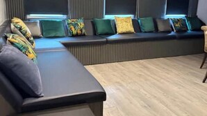Ein modernes Wohnzimmer mit einer Eckcouch, einem Couchtisch und einem großen Fenster mit Jalousien.