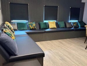 Ein modernes Wohnzimmer mit einer Eckcouch, einem Couchtisch und einem großen Fenster mit Jalousien.