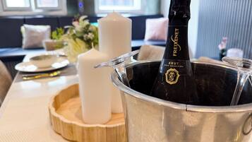 A bottle of Freixenet Brut champagne in a metal bucket on a wooden tray, with white candles and a vase of flowers in the background.