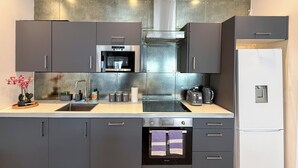 Een moderne keuken met grijze kastjes, roestvrijstalen apparatuur en een ingebouwde oven.