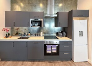 A modern kitchen with grey cabinets, stainless steel appliances, and a built-in oven. - Yellow Submarine Apartments - Sleeps 19 (Liverpool)