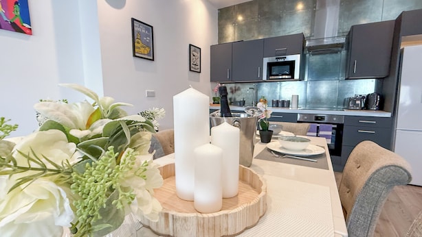 Een moderne keuken met roestvrijstalen apparatuur, een eethoek met een witte tafel en een bloevas.