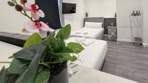 Een moderne hotelkamer met een bed, een televisie, een plant en een douche.