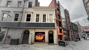 Een gebouw met een grote, kleurrijke muurschildering aan de voorkant, een bord met de tekst 'Wetherspoon' en een gevel van baksteen.