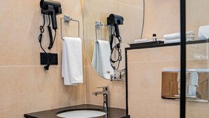 A modern bathroom with a black vanity, a white sink, a toilet, and a mirror. - Grand Ambassador Business Hotel (Kathmandu)