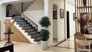 Un interior moderno con una escalera, una planta en maceta, un comedor y un jarrón decorativo.