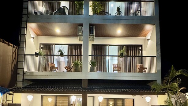 Un edificio de varios pisos con balcones, piscina y mobiliario de exterior.
