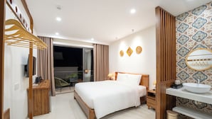 Habitación de hotel moderna con cama, muebles de madera, baño con lavamanos y espejo, y vistas al exterior.
