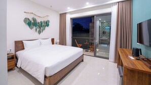 Una habitación de hotel moderna con una cama grande, un escritorio, un televisor y un balcón con cortinas.