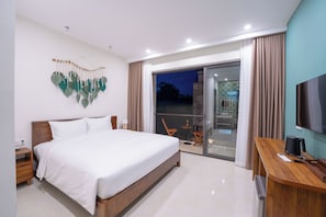 Una habitación de hotel moderna con una cama grande, un escritorio, un televisor y un balcón con cortinas.