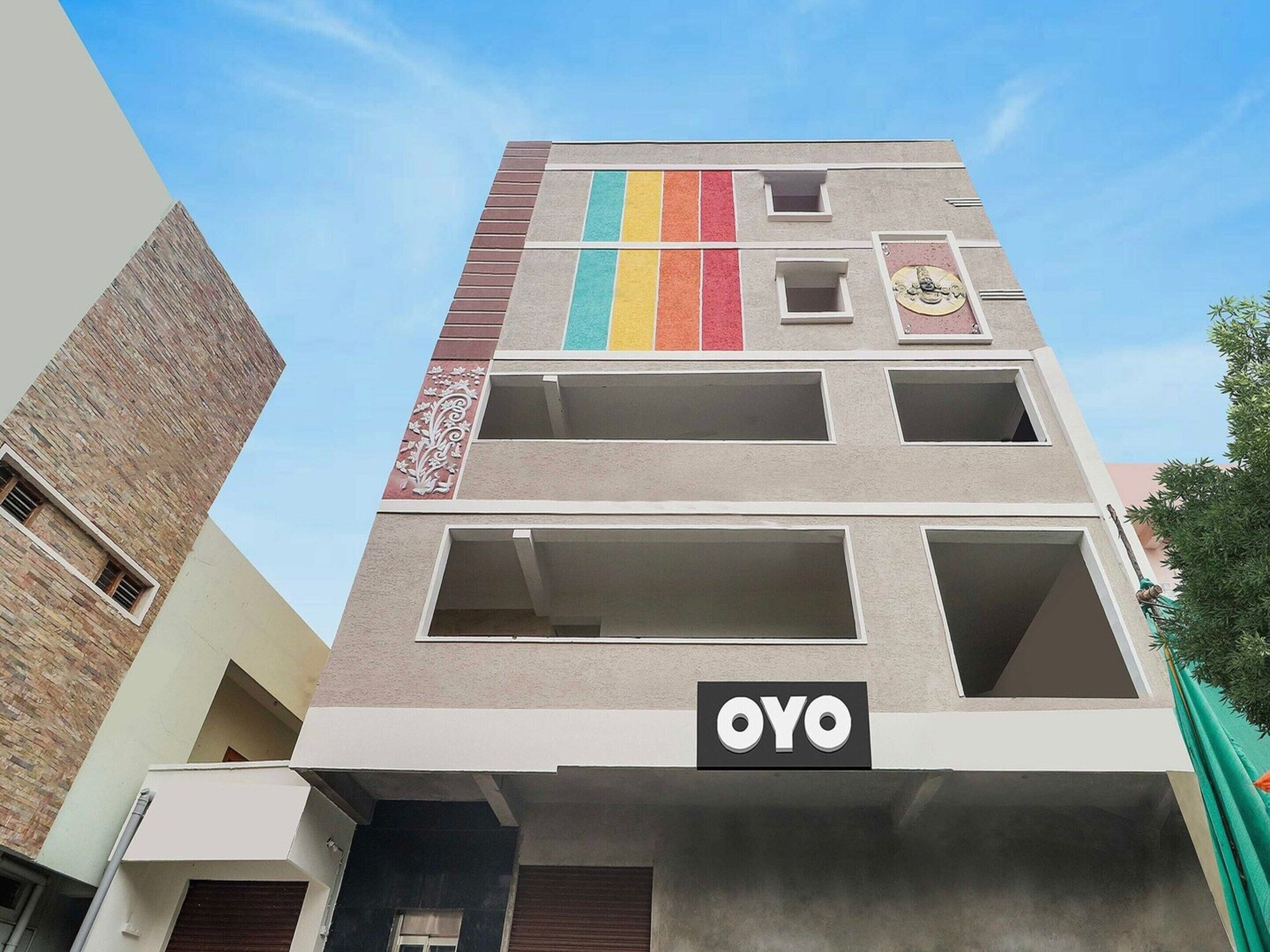 A multi-story building with a prominent 'OYO' sign on the facade, featuring a mix of brick and plaster textures, and a decorative emblem above the sign.