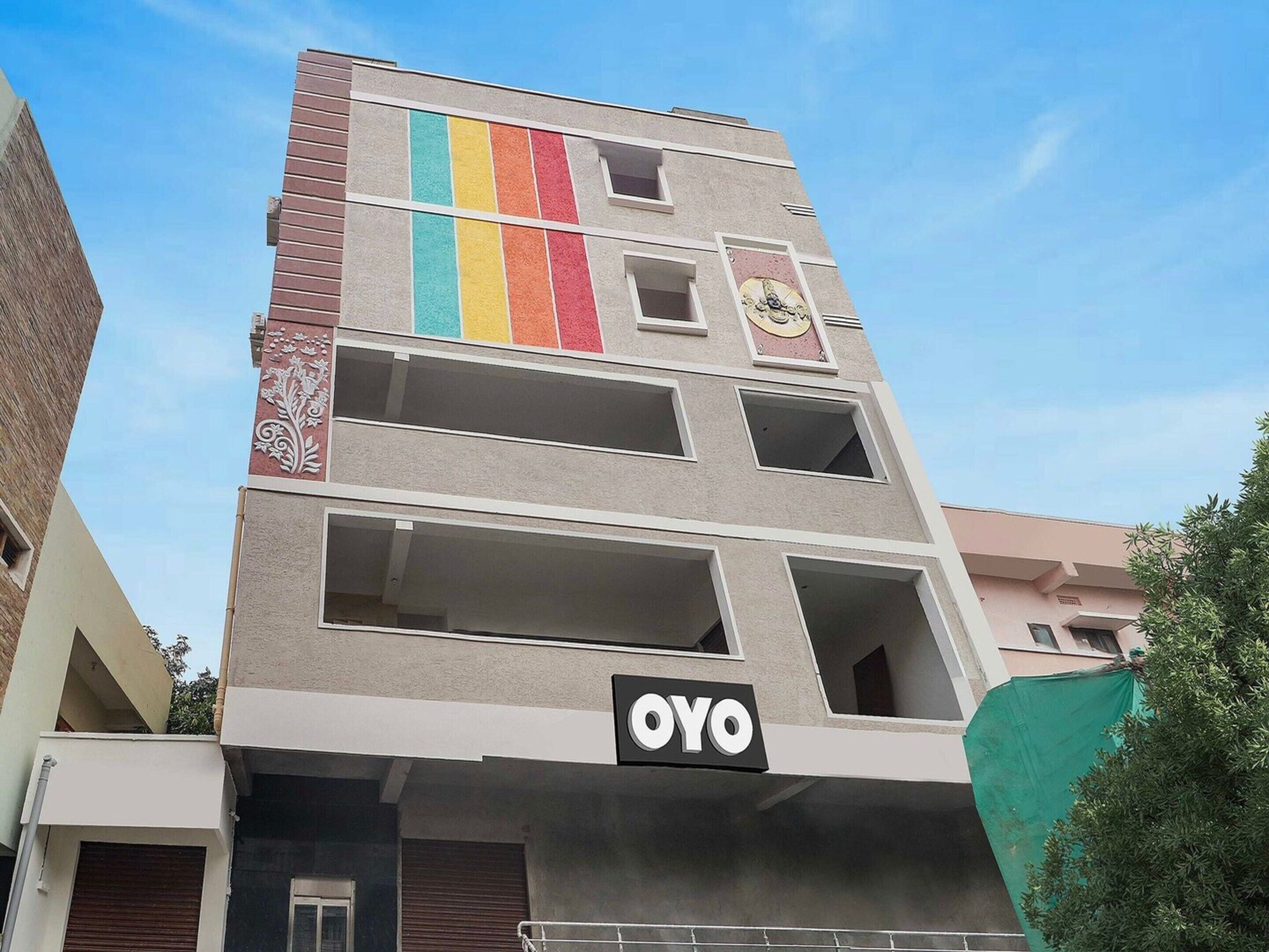 Un immeuble à plusieurs étages, avec une grande enseigne « OYO » bien visible au rez-de-chaussée.