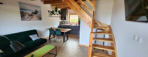 Una sala moderna con un sofá verde, una mesa de comedor de madera y una escalera.