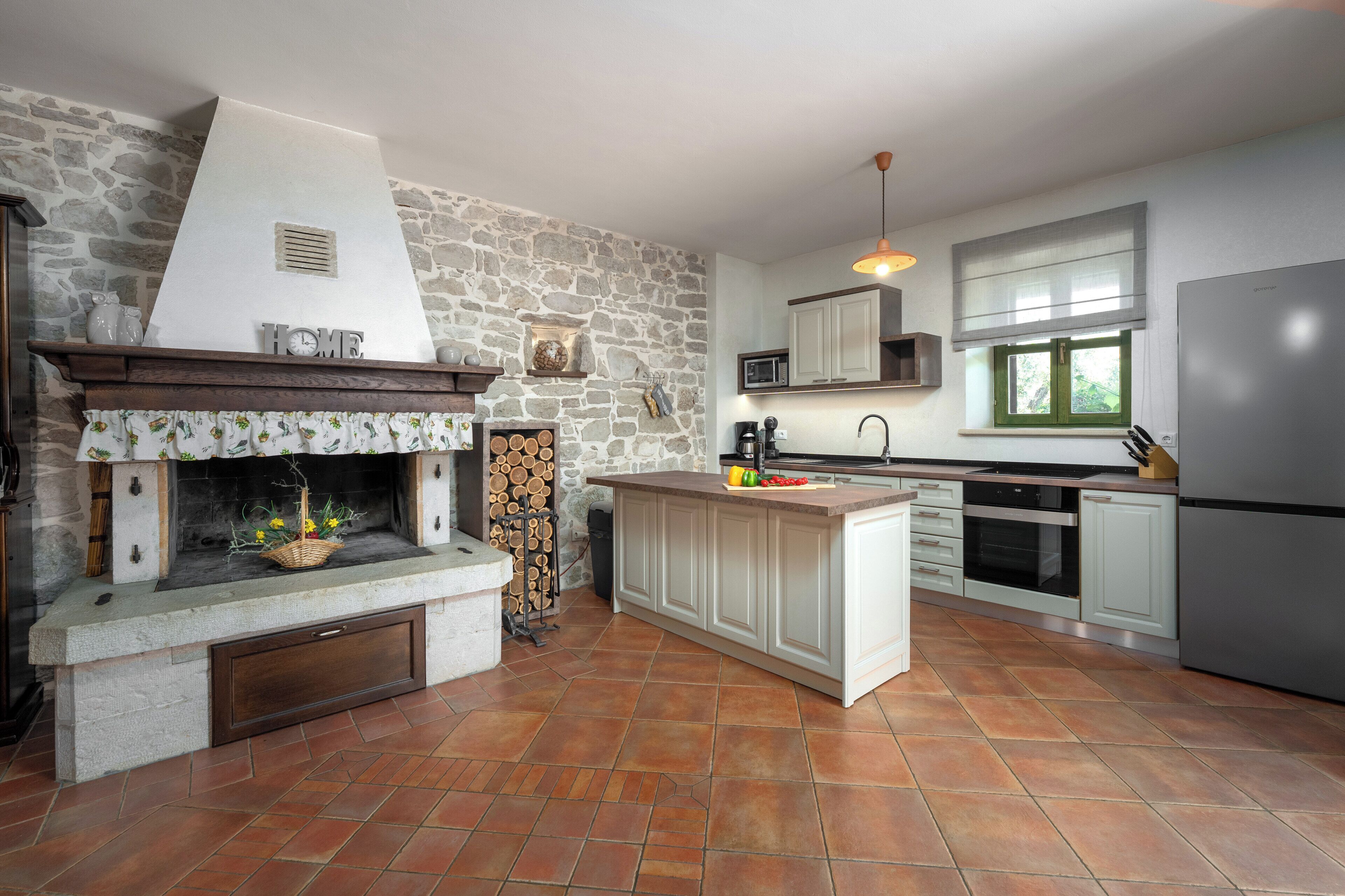 Eine Küche mit Steinwand, Kamin, Kochinsel und modernen Geräten.