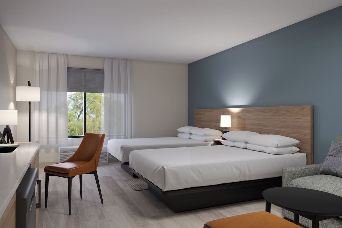 Hotellihuone, jossa on kaksi sänkyä, työpöytä, tuoli, sohva ja sohvapöytä.