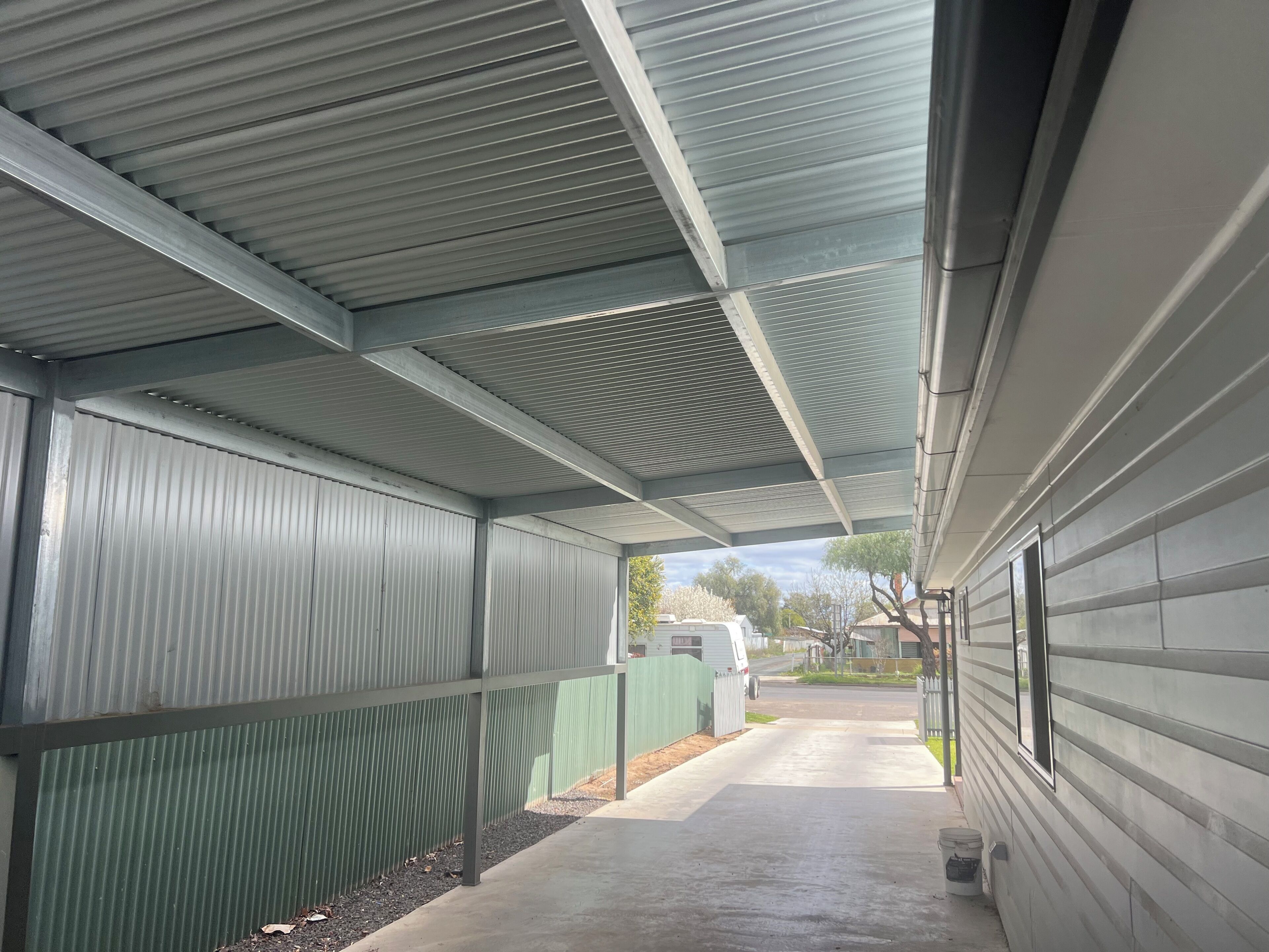 A covered walkway with metal siding and a concrete path.
