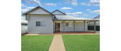 A modern two-story house with a covered porch, a visible garage, and a well-maintained lawn.