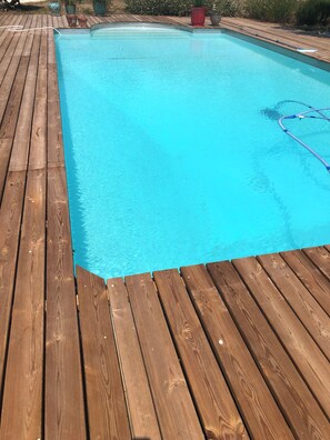 Eine Holzterrasse umgibt einen rechteckigen Pool.