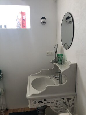 Ein Badezimmer mit einem weißen Waschbecken, einem Spiegel und einem Fenster.