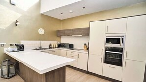 A modern kitchen with a central island, built-in appliances, and a clock on the wall. - York City Centre | Shambles & Minster Walk (York)
