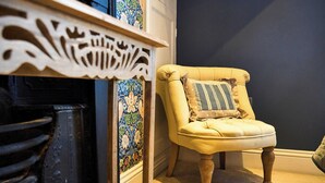 A chair with a cushion, a patterned wall, and a decorative shelf. - York City Centre | Shambles & Minster Walk (York)