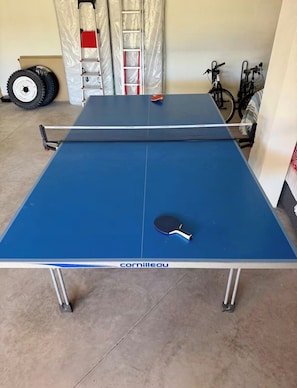 Ein blauer Tischtennis-Tisch mit Netz, Schläger und Metallbeinen.