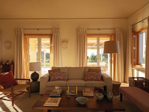 Ein Wohnzimmer mit einer Couch, einem Couchtisch und Blick ins Freie durch große Fenster.