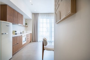 A modern kitchen with wooden cabinets, a white refrigerator, and a dining area with a chair.